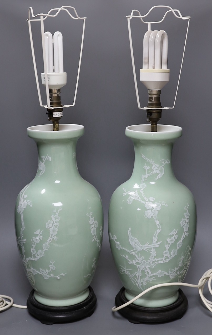 A pair of Chinese slip decorated celadon ground lamps, 40cms high including stands